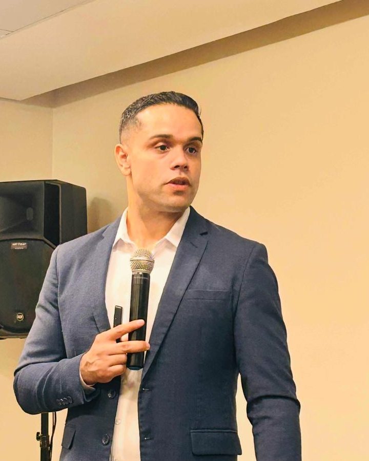 Hitalo Colares falando ao microfone durante uma palestra sobre leilão de imóveis